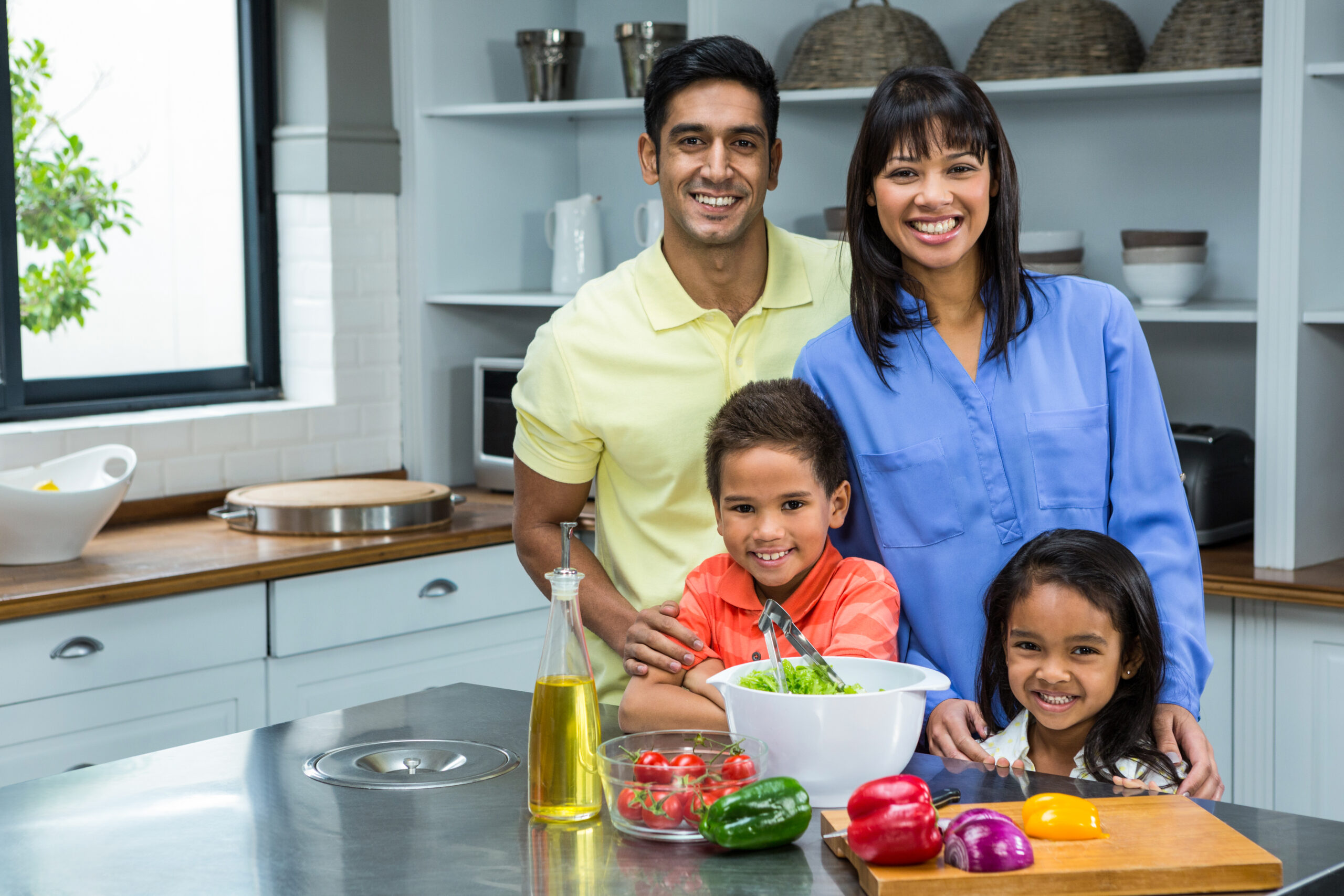 Portrait of happy family in the kitchen preparing salad
